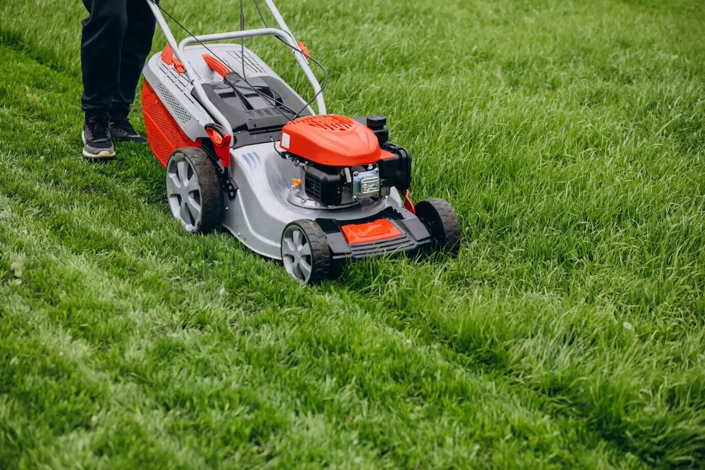 A man cutting grass with a lawn mower in the backyard.